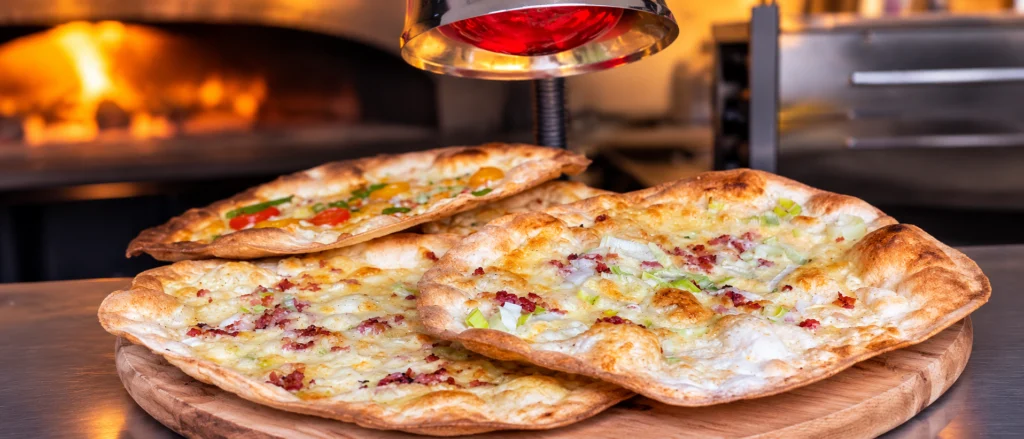 Ambachtelijke flammkuchen met spek, kaas en groenten vers bereid onder de warmtelamp